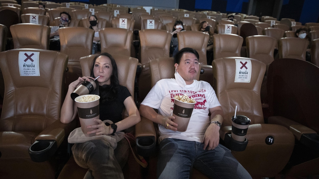 Des gens sont assis dans une salle de cinéma en respectant le principe de distanciation sociale.