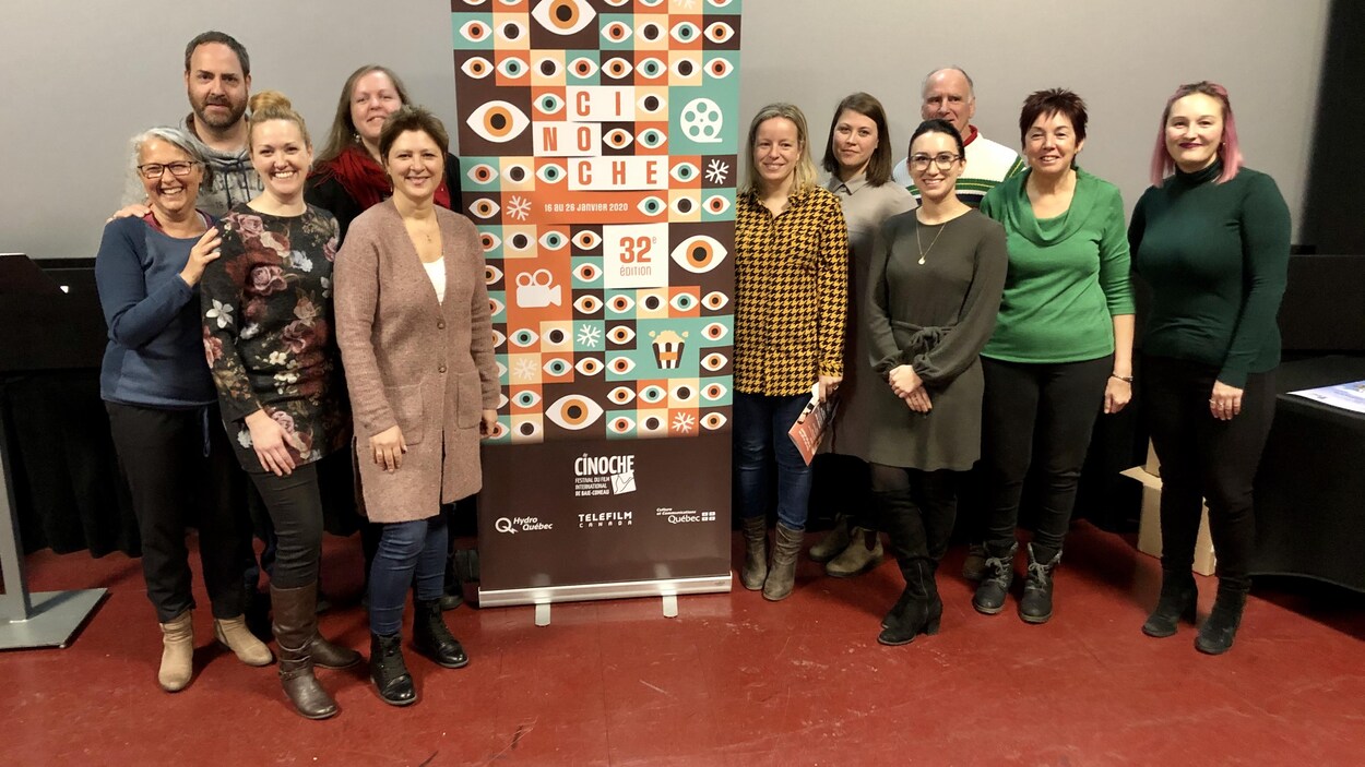 Un groupe de personnes à côté d'une affiche du Festival Cinoche.