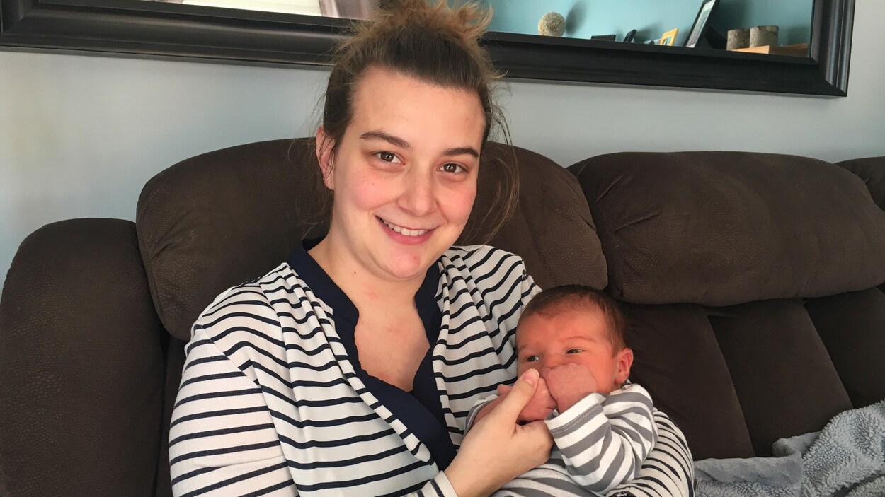 Une jeune mère souriante tient un bébé dans ses bras