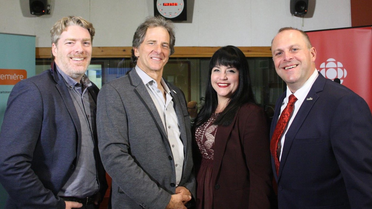 Les quatre candidats sourient à la caméra, dans le studio radio de Radio-Canada.