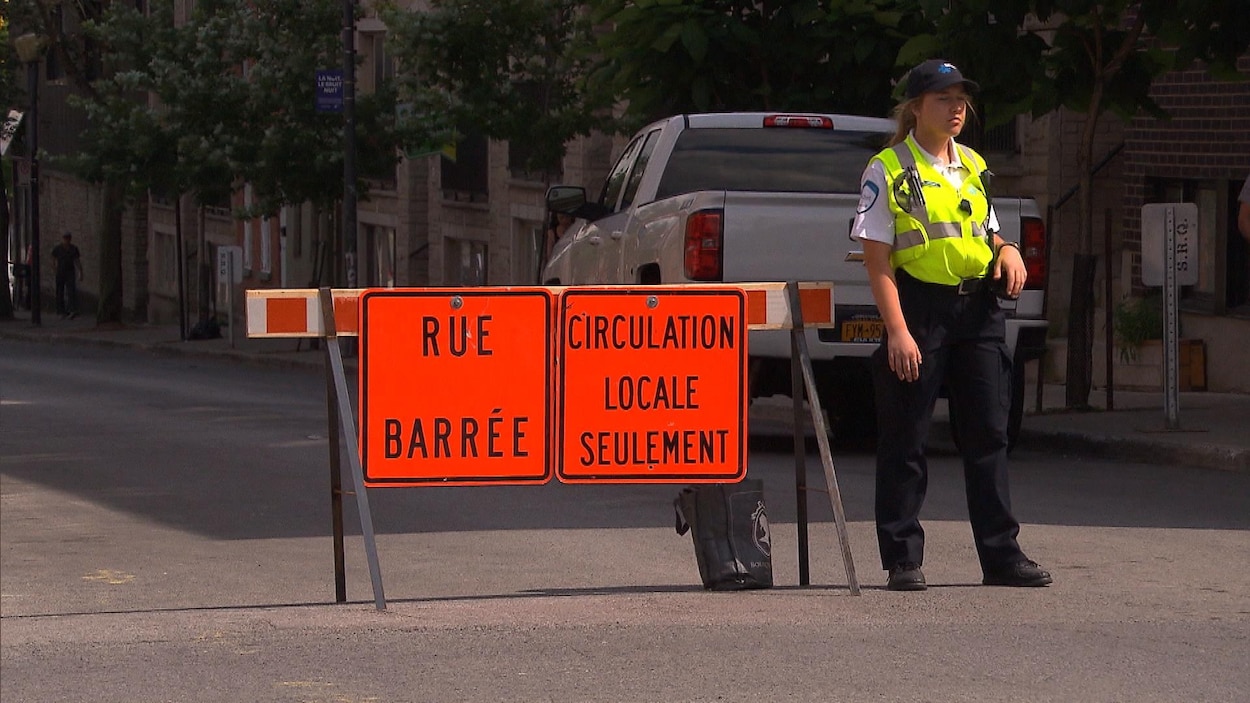 Une policière devant une rue fermée à la circulation Une policière devant une rue fermée à la circulation
