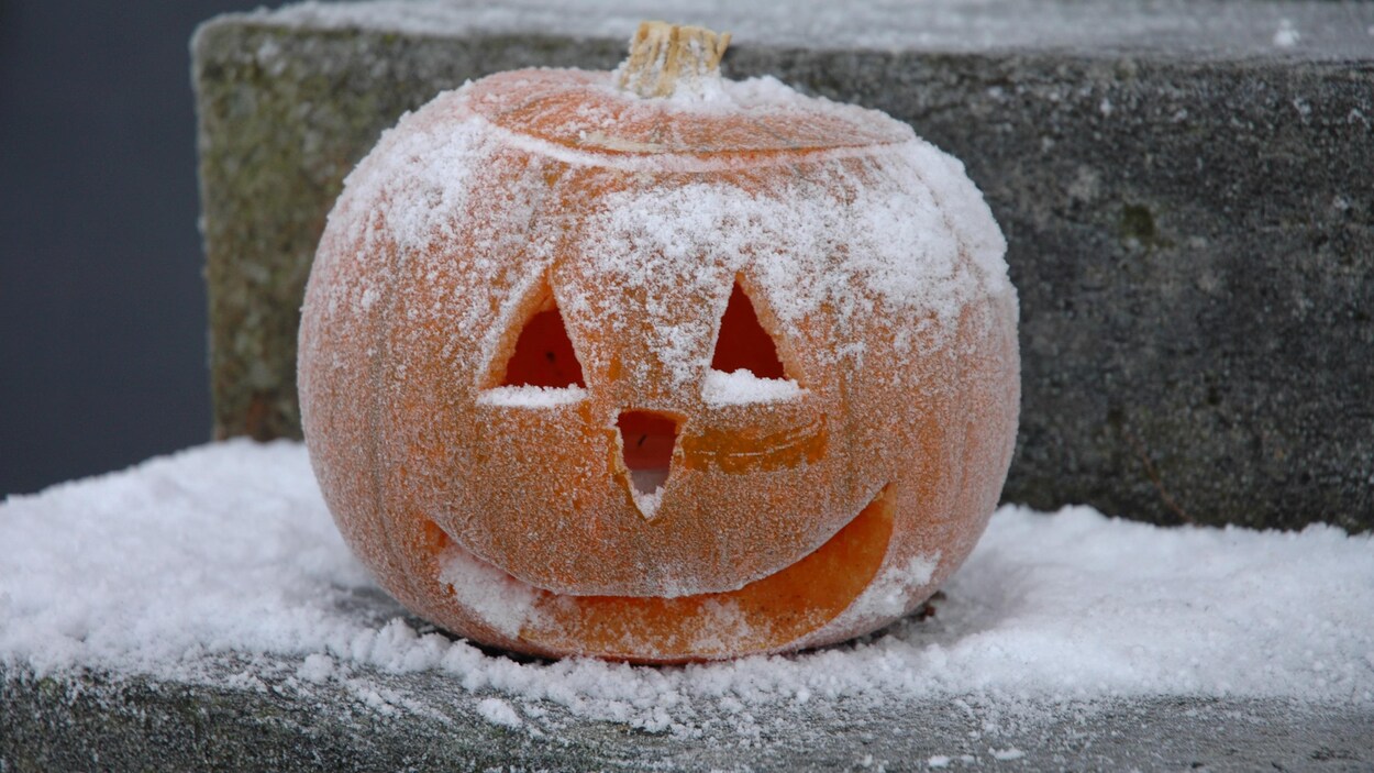 Une citrouille décorée pour l'Halloween sous la neige dans un escalier.