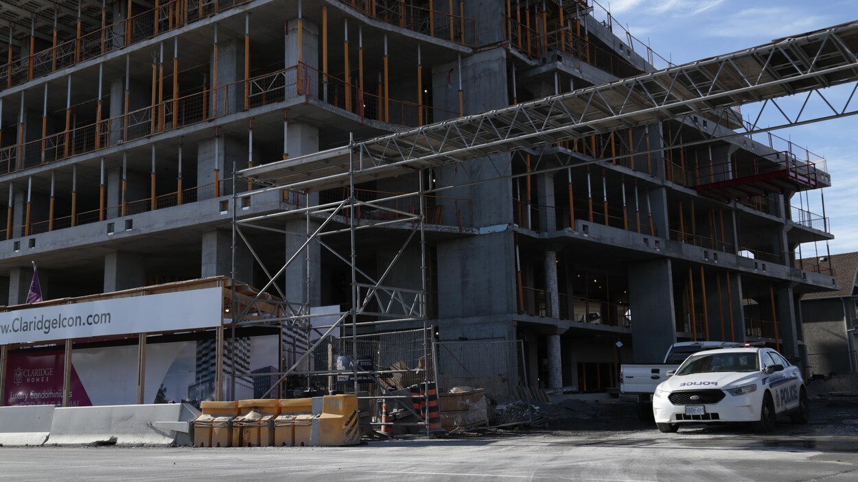 Une voiture de police est stationnée à côté d'un immeuble en construction.
