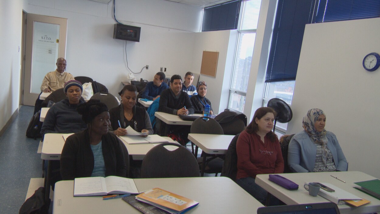 Des adultes de diverses origines ethniques assis dans une salle de classe.