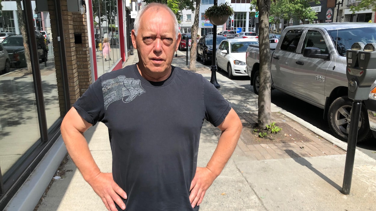 Un homme pose les mains sur les hanches, sérieux, au centre-ville de Rouyn-Noranda.