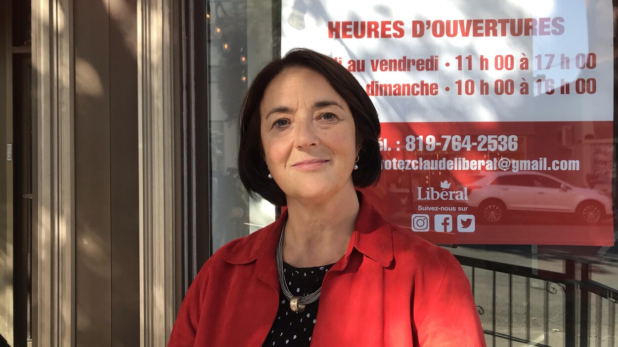 La candidate se tient debout dehors devant son local électoral.