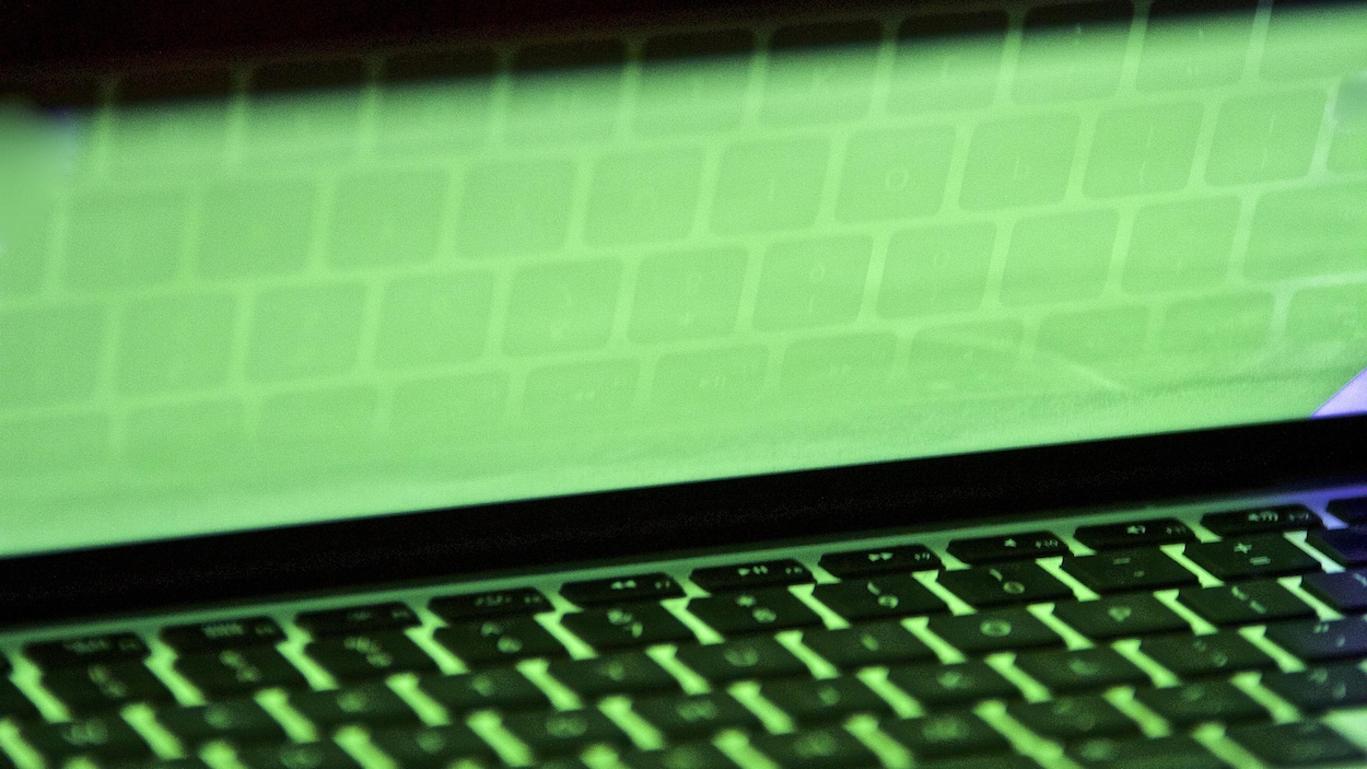 Un clavier d'ordinateur portatif se reflète sur un écran.