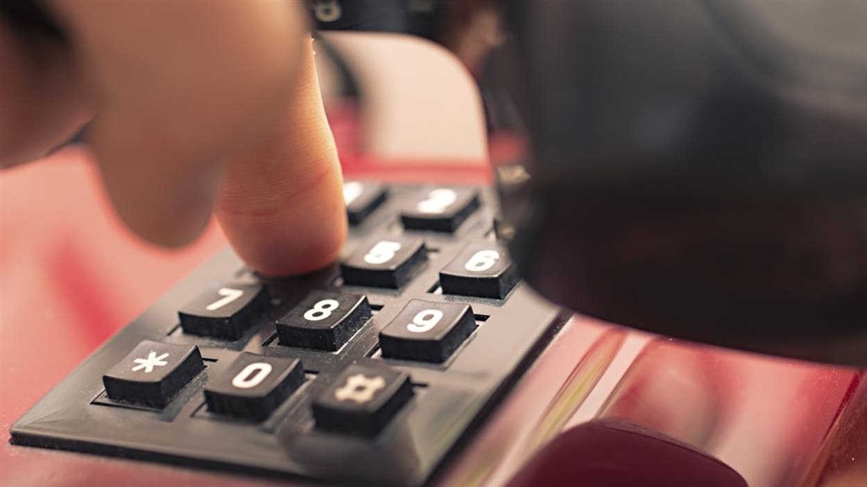 Une personne compose un numéro de téléphone.
