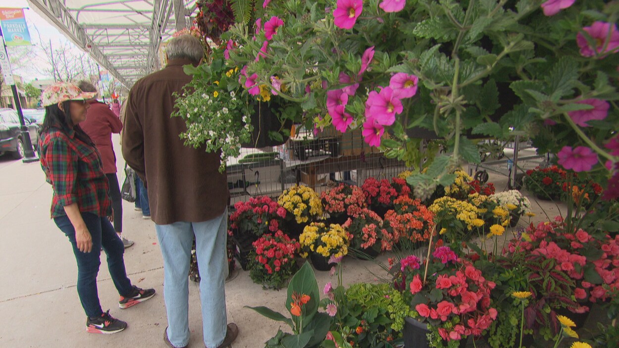Des passant regardent des fleurs dans une pépinière.