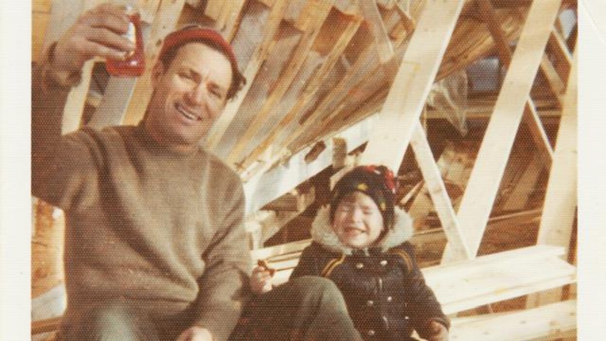 Une photo d'archives d'un père et son fils assis près d'une coque de navire en construction.