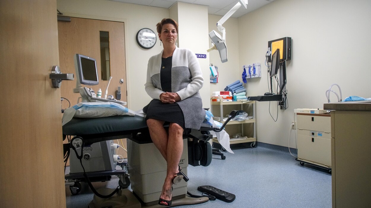 La docteure Colleen McNicholas est assise sur une table de travail dans une salle de traitement de la clinique.