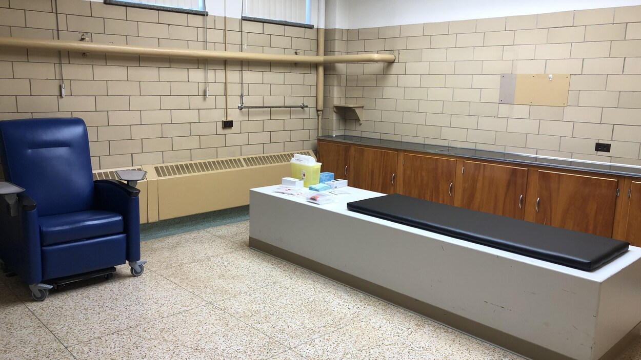 Un sofa bleu dans une salle de clinique avec un lit pour les patients