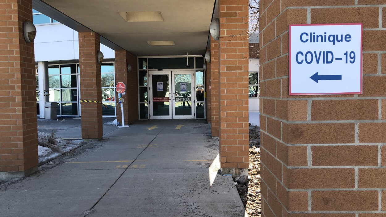 Un panneau indiquant le chemin vers une clinique de dépistage de la COVID-19 à l'extérieur d'un bâtiment.