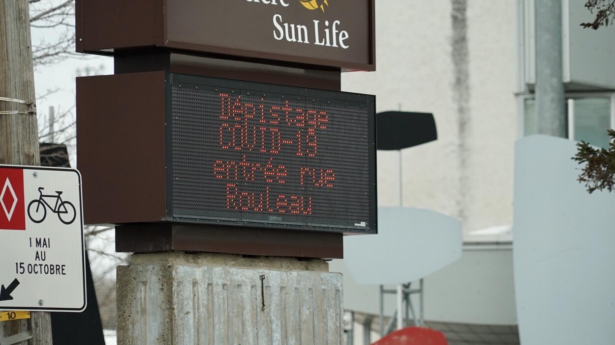 Une affiche indiquant « dépistage covid-19 entrée rue Rouleau »