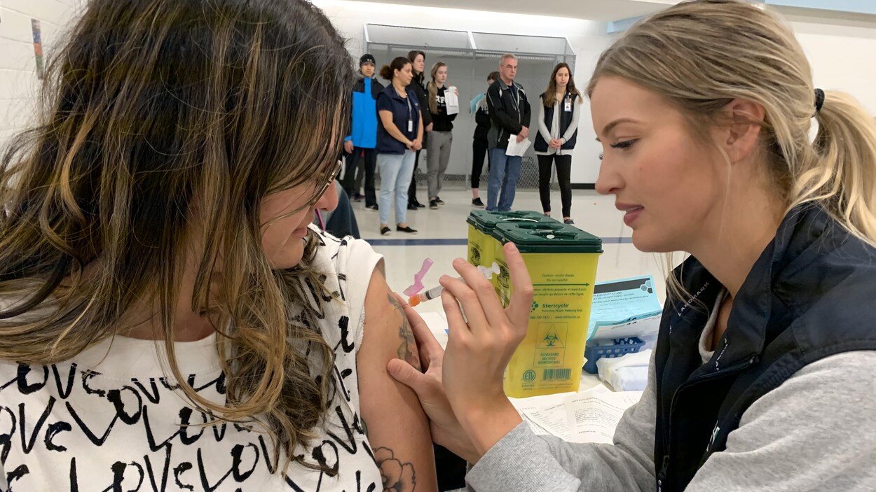 Une infirmière vaccine une femme.