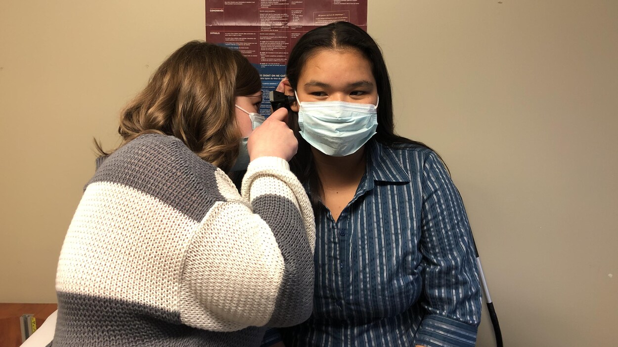 Une infirmière ausculte l'oreille d'une femme autocthone.