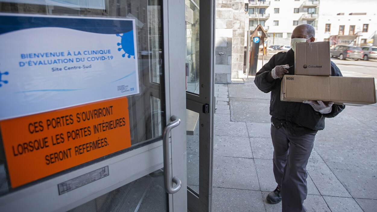 Un livreur portant un masque s'apprête à entrer dans la nouvelle clinique consacrée au dépistage du coronavirus à Montréal.