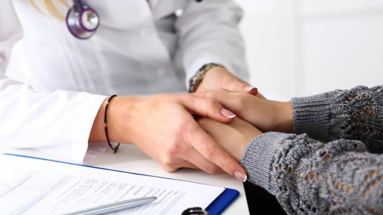 Un médecin prend les mains d'une patiente.
