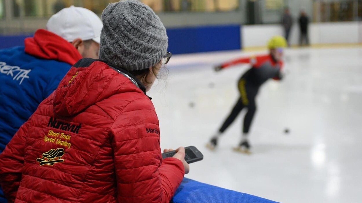 L'entraîneuse Martine Dupont regarde un patineur sur la glace.
