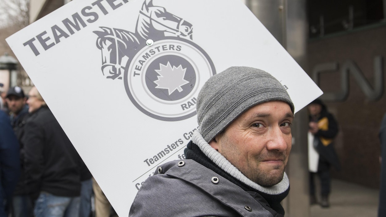 Un employé du CN porte une pancarte à l'extérieur du siège social du CN à Montréal, le mardi 26 novembre 2019.