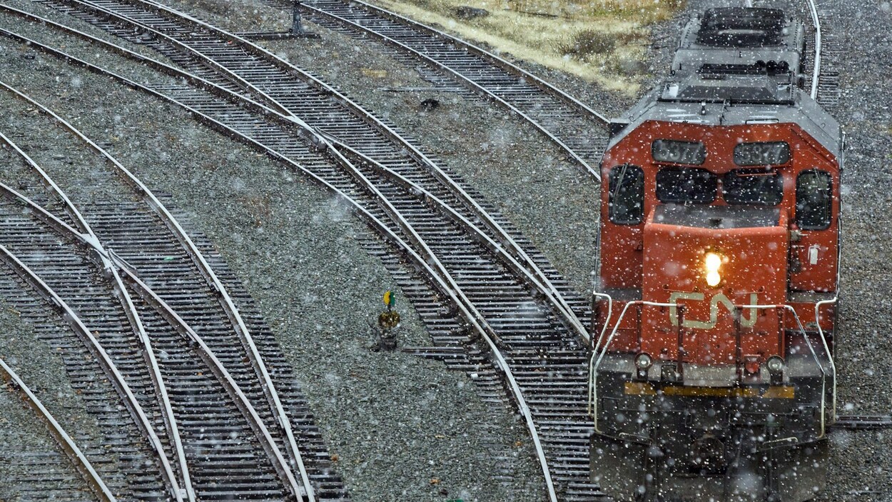 Une locomotive du CN circule sur des rails par temps pluvieux.