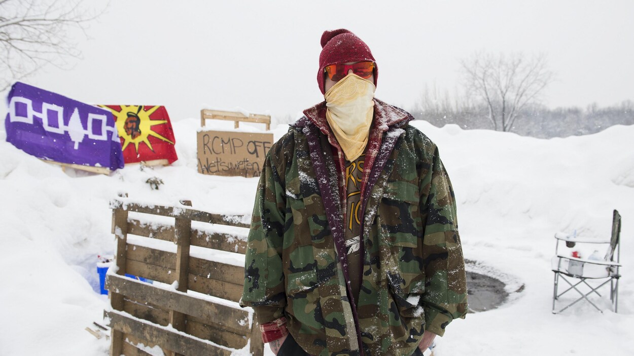 Un homme masqué se tient debout dans la neige et pose pour la caméra.