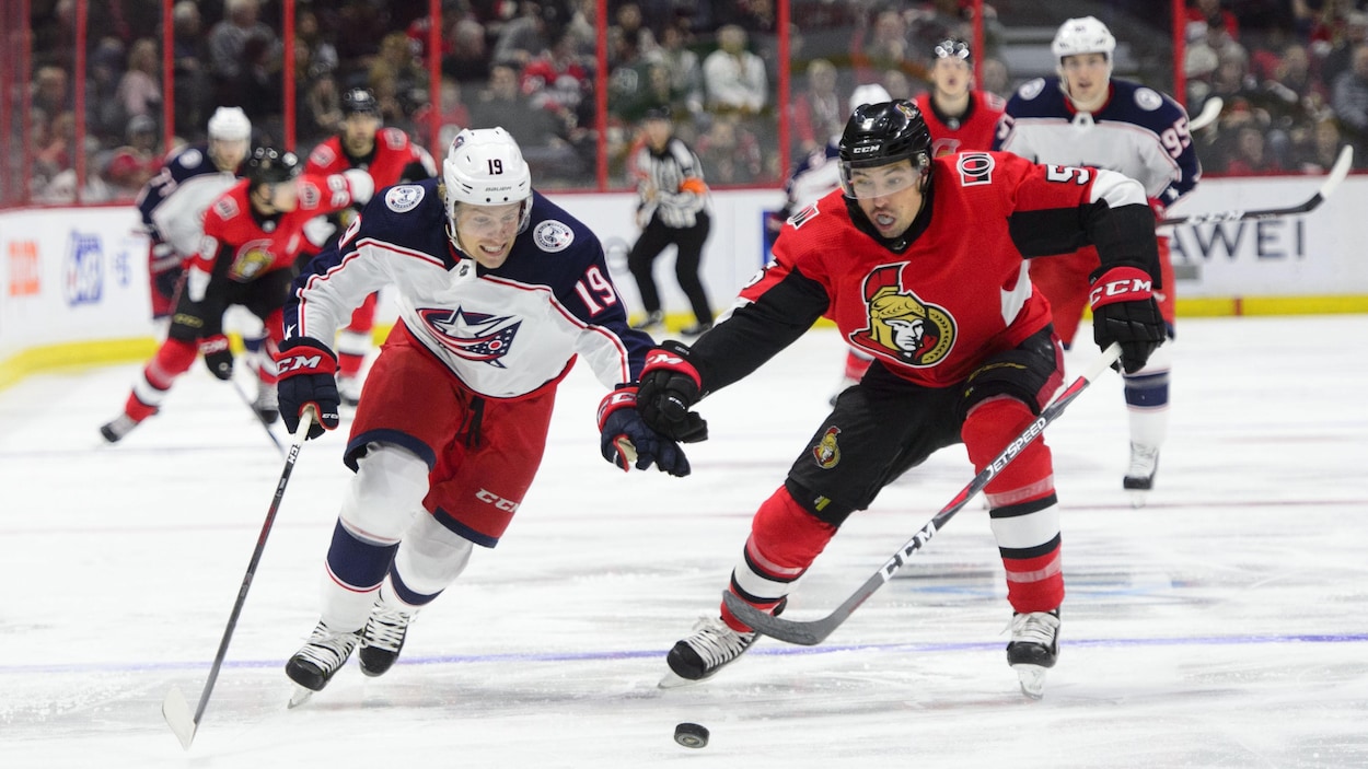 Les deux joueurs de hockey se disputent la rondelle.