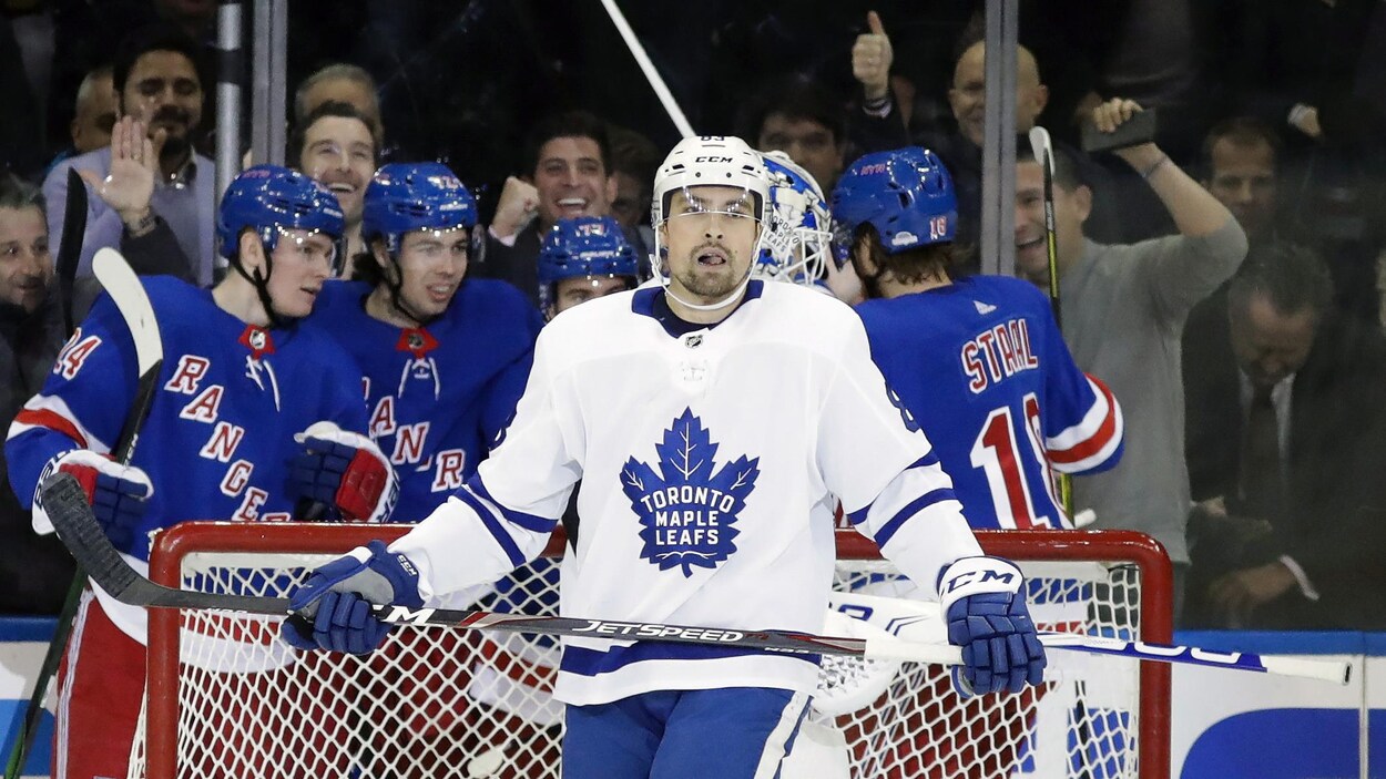 Il regarde au loin pendant que des joueurs des Rangers célèbrent un but.