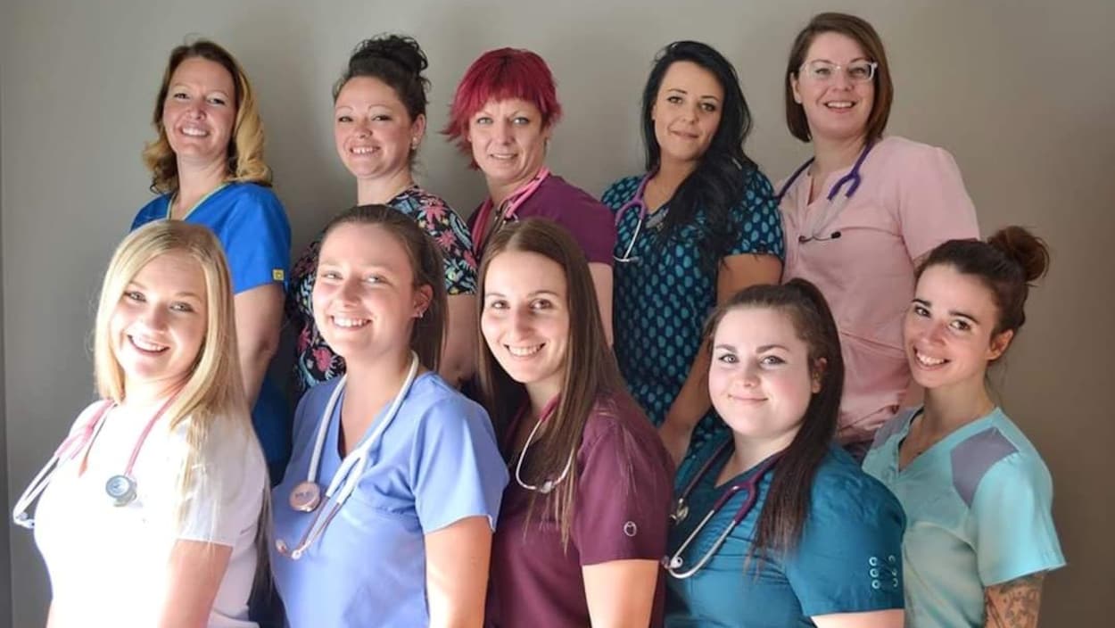 10 femmes portant des habits d'infirmière, stéthoscope au cou, posent pour une photo de finissantes.