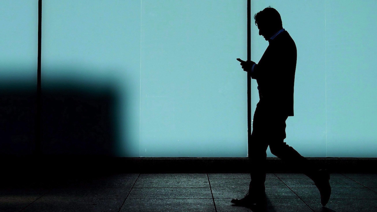 Une photo d'un homme qui marche en regardant son téléphone portable.