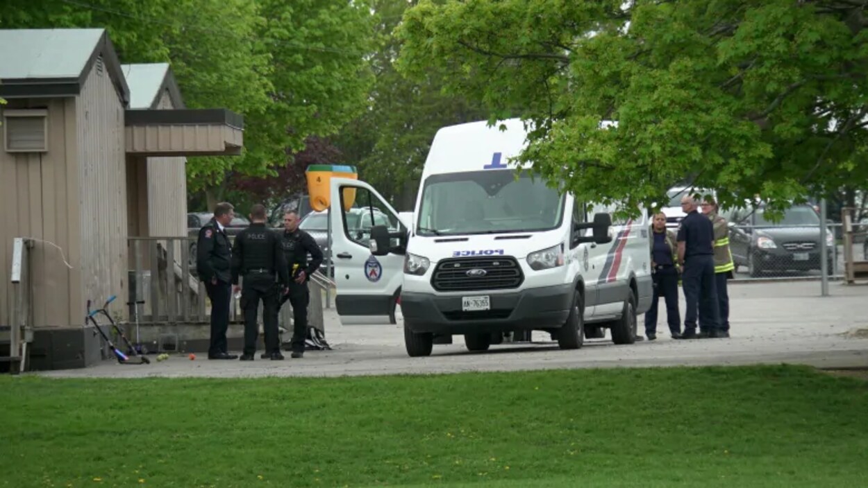 Photo de policiers et de pompiers qui se tiennent debout à côté d'une camionnette de police.