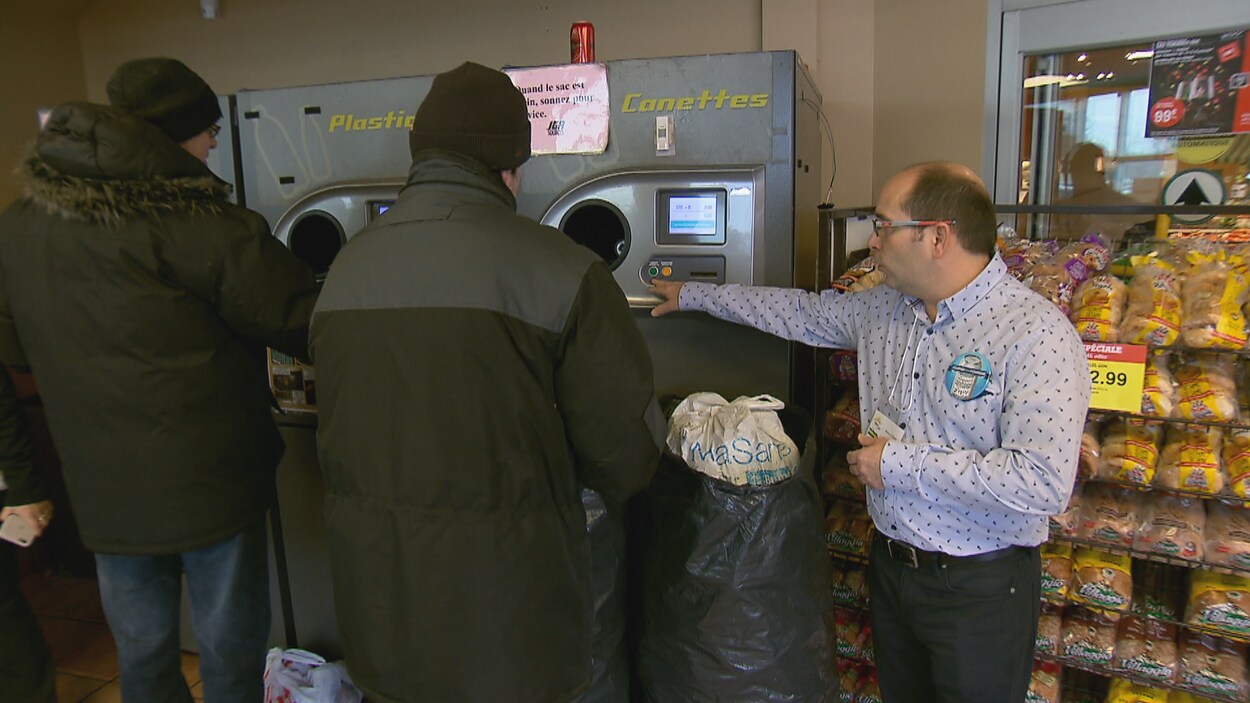Des personnes retourne des canettes consignées dans une machine à l'entrée d'un supermarché Des personnes retourne des canettes consignées dans une machine à l'entrée d'un supermarché