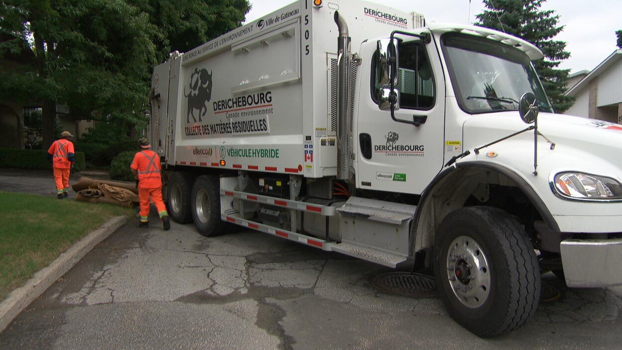 Deux éboueurs collectent des déchets.