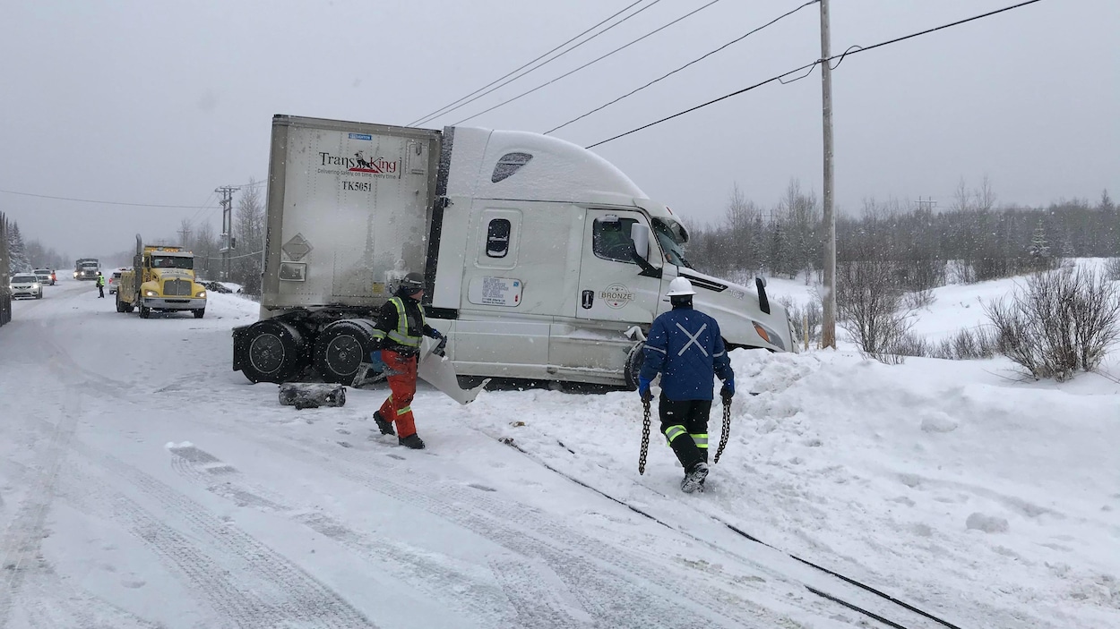 Un camion est pris sur le bord de la route et des véhicules attendent derrière.