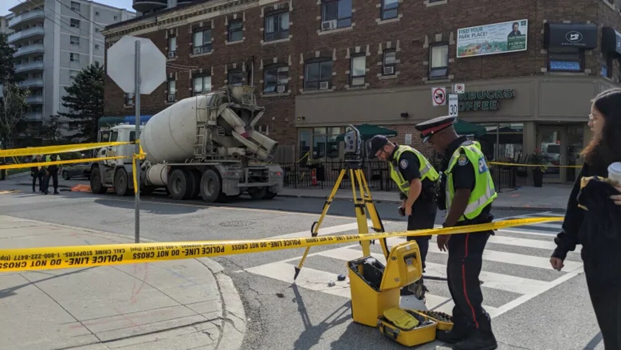 Des policiers et des passants sont sur une scène d'accident devant un Starbucks, une bétonnière montée sur camion est sur l'accotement.
