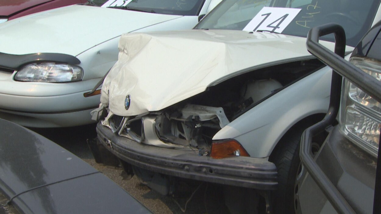 Un caport d'auto défoncé, quelques voitures sont stationnées auprès de celle qui a subi un accident.