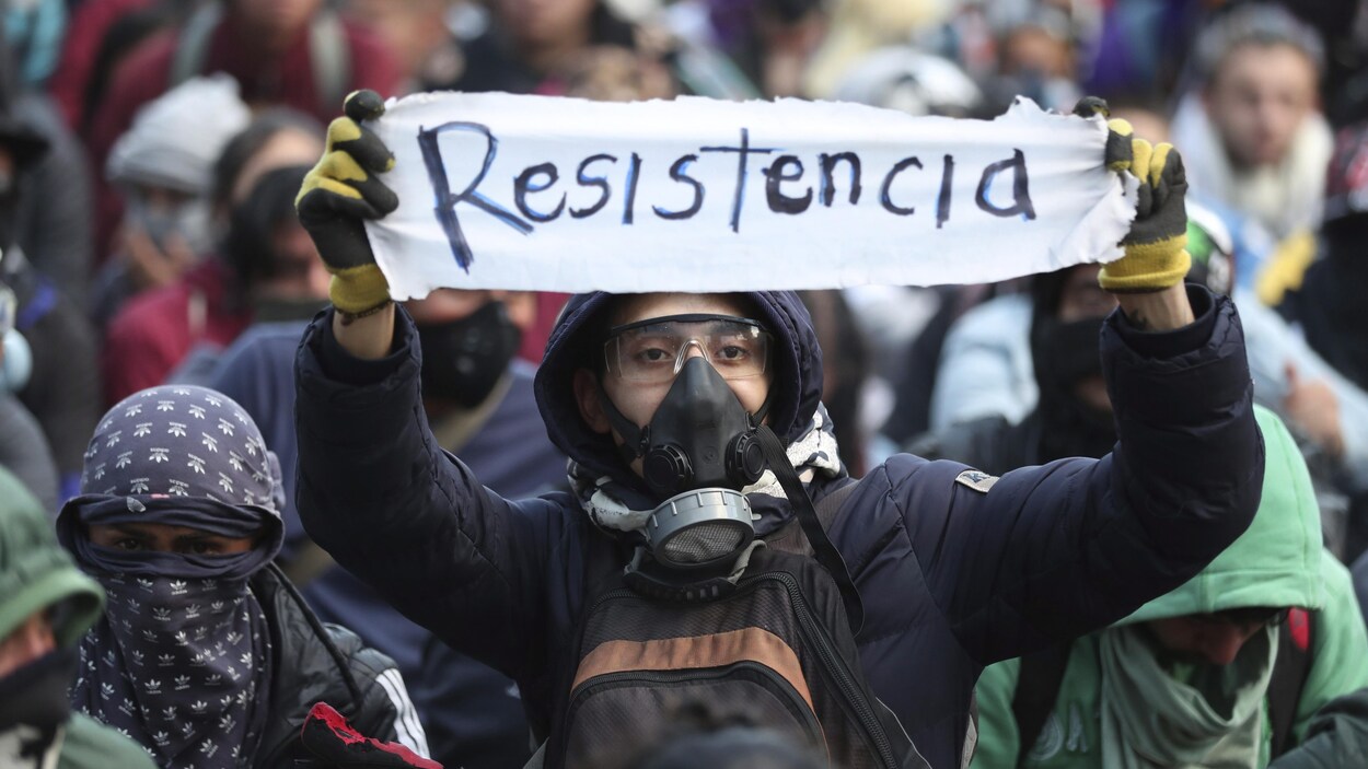 Un manifestant brandit un morceau de tissu sur lequel est écrit le mot «résistance».