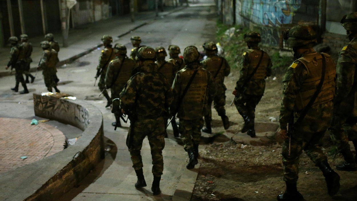 Des soldats marchent dans une rue la nuit.