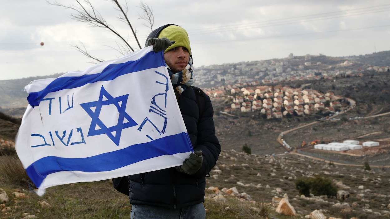 Un colon tient un drapeau israélien sur lequel il a inscrit des slogans dans la colonie d'Amona, située non loin de Ramallah, en Cisjordanie. L'armée israélienne a entrepris l'évacuation de ses quelque 300 résidents mercredi.