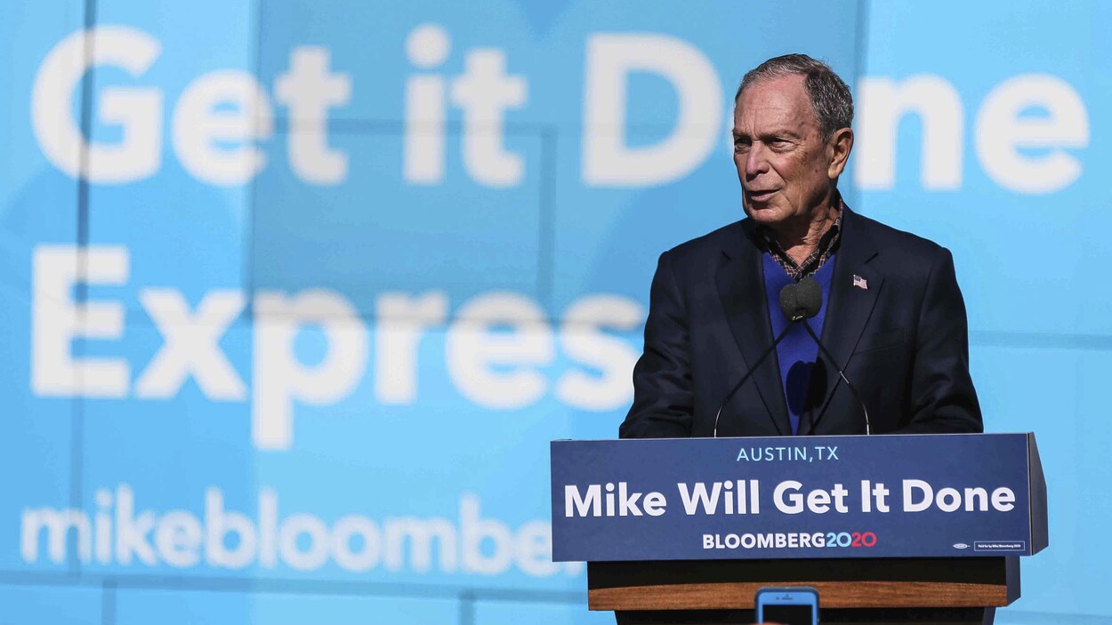Plan large de Michael Bloomberg sur une tribune, derrière un micro.