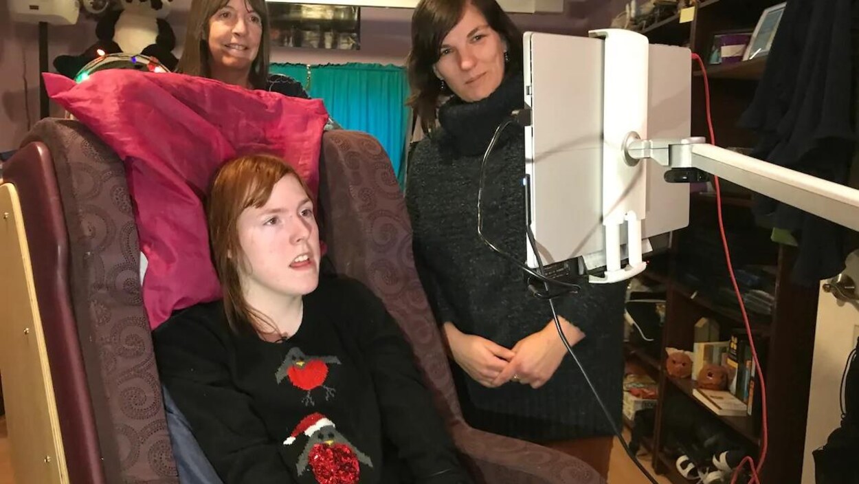 Eva von Flotow avec sa mère Lyne et son ergothérapeute Melissa Croskery regardant un écran.