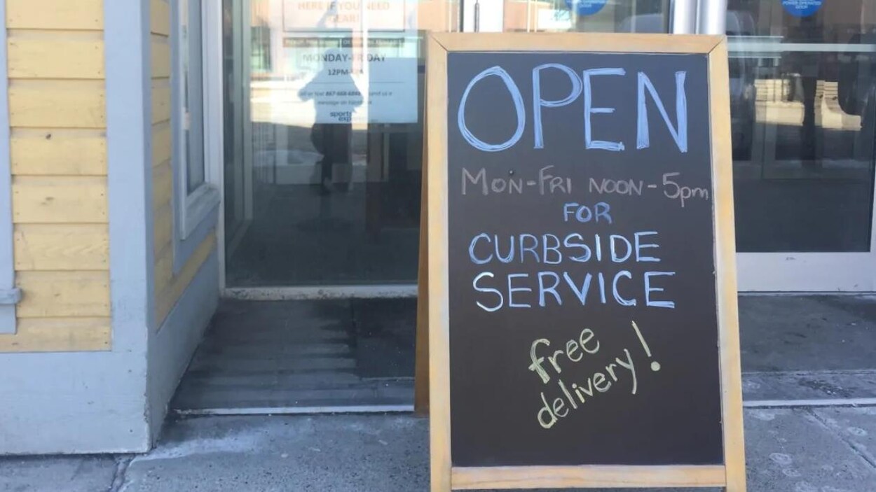 Une pancarte invitant la clientèle à attendre sa commande sur le trottoir.