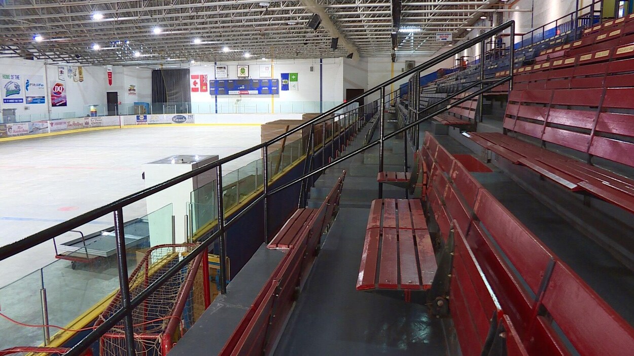 L'intérieur de l'aréna, avec la glace et des bancs rouges.