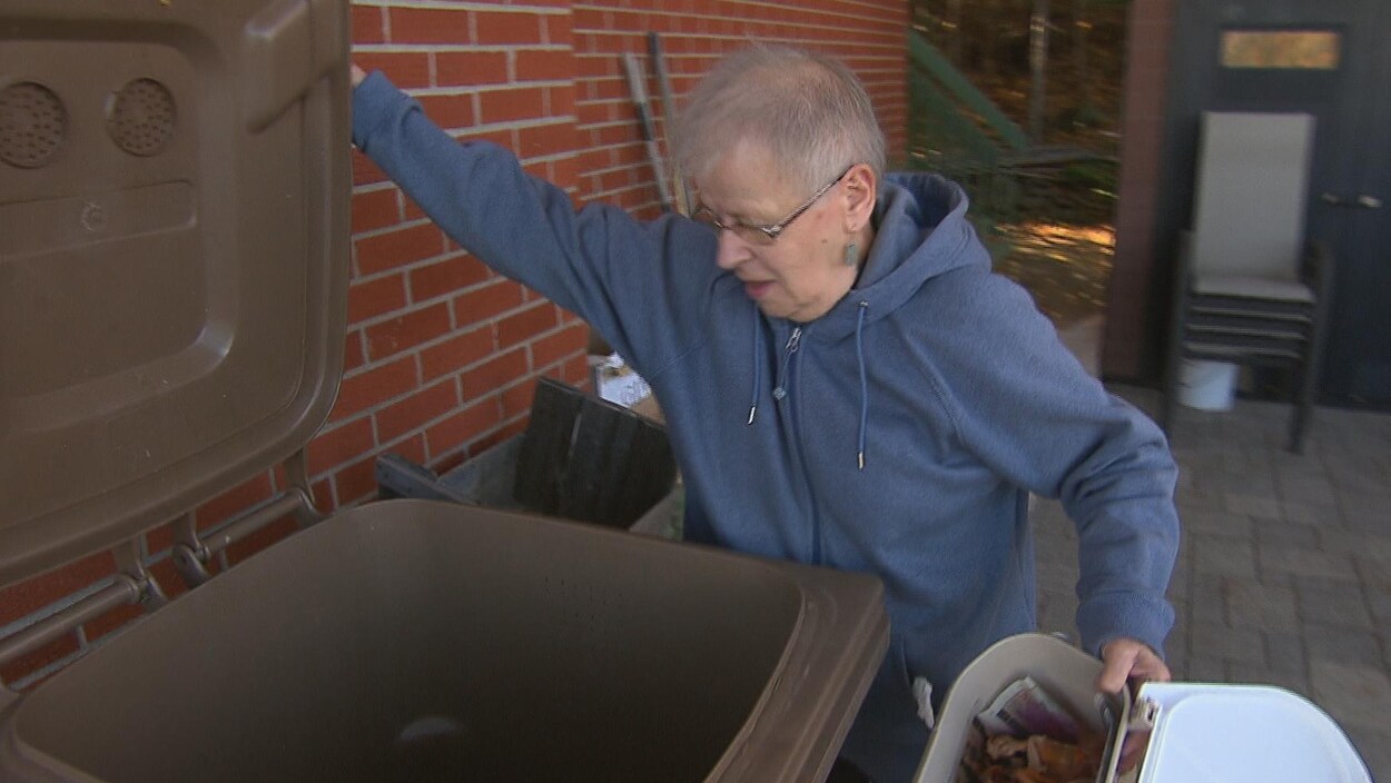 Une résidente de Gaspé s'apprête à transférer son compostage de son petit bac de cuisine vers le brun à l'extérieur.