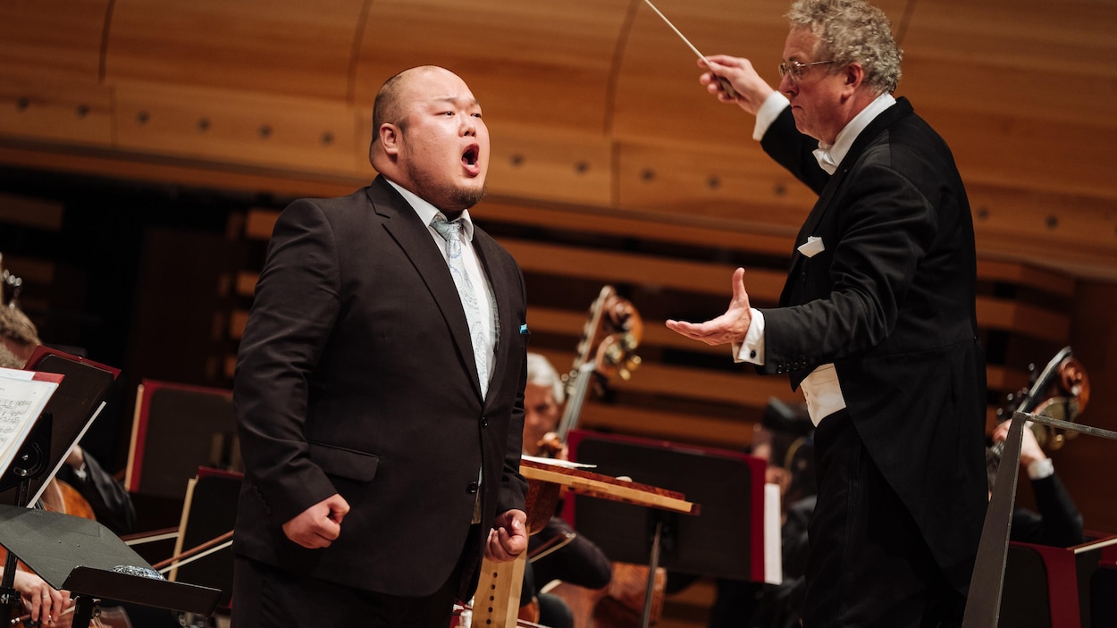 Un homme chante devant un orchestre.