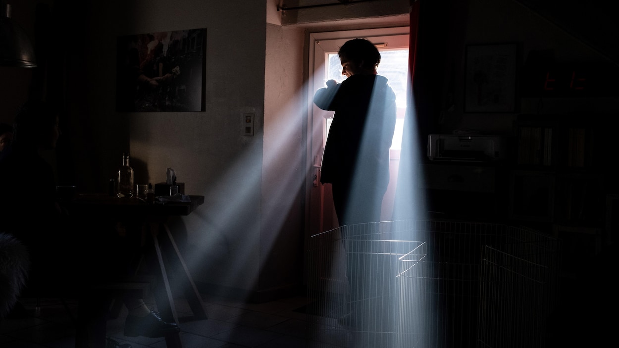 La silhouette d'une personne se profile devant une fenêtre par laquelle entrent les rayons du soleil.