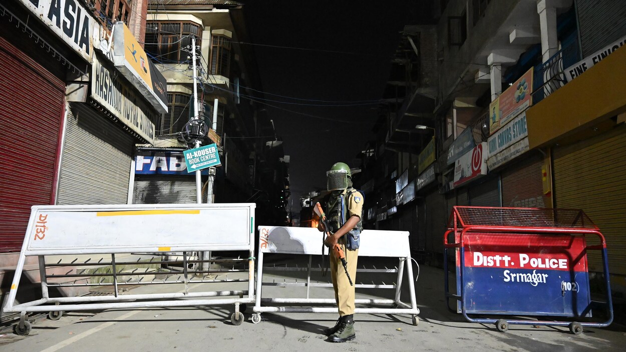 Un homme armé debout dans la rue devant une barricade.