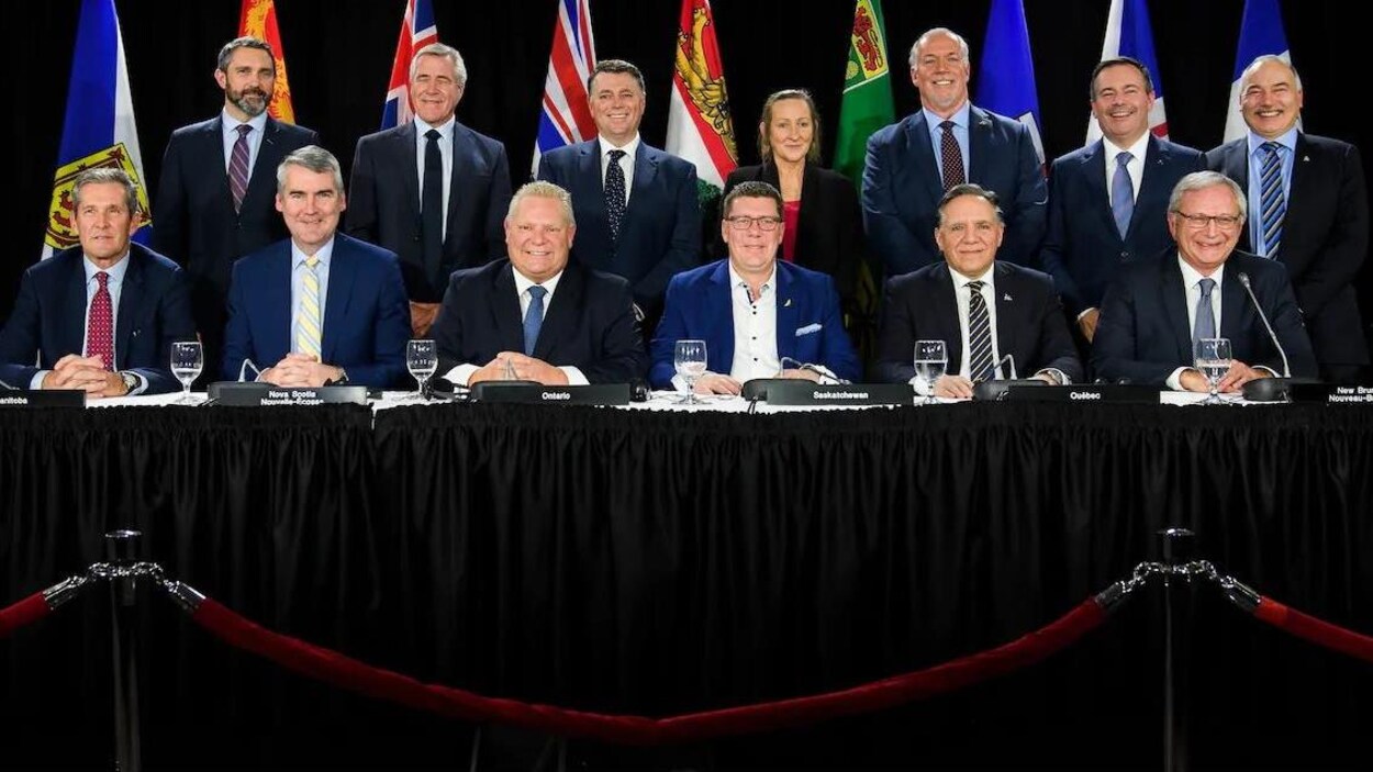 Les 13 premiers ministres des provinces et territoires canadiens sourient à la caméra, placés en deux rangées.