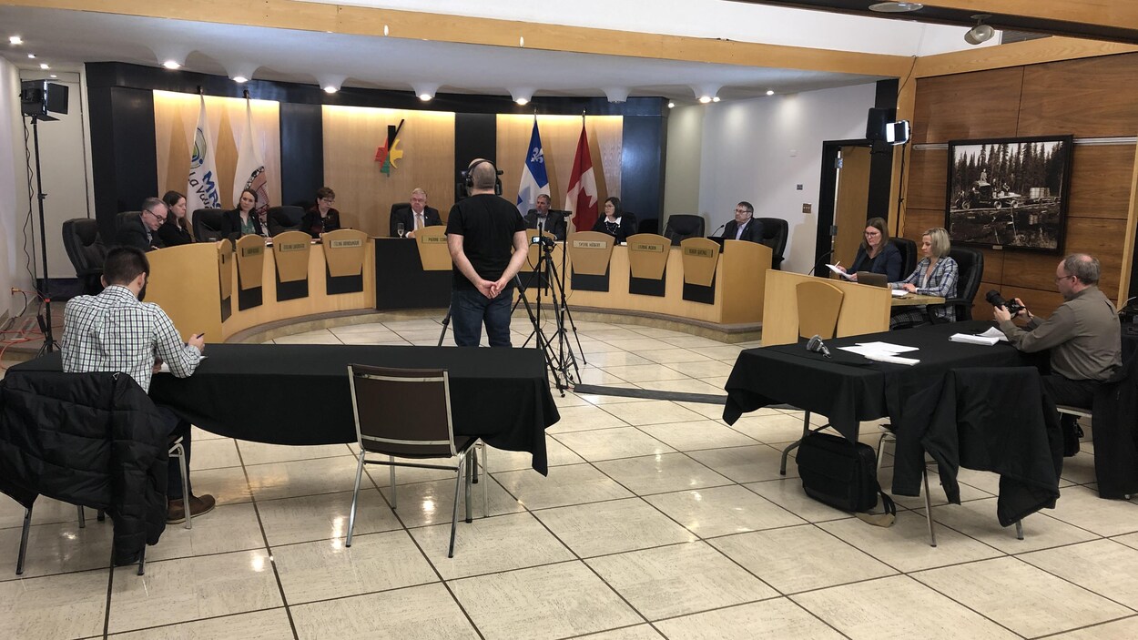 La salle du conseil municipal avec les sièges des élus et les tables pour les journalistes.