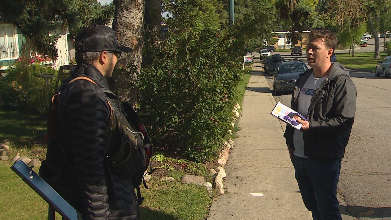 Un électeur discute avec Colin Korol sur une rue verdoyante.